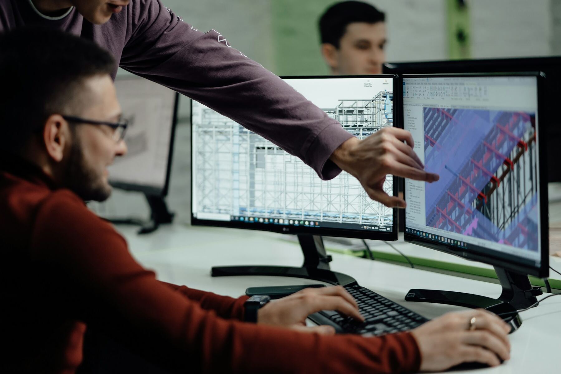 Two engineers reviewing a 3D building model on screens