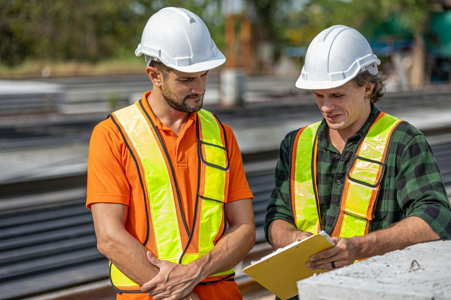 Two site engineers in hard hats reviewing plans
